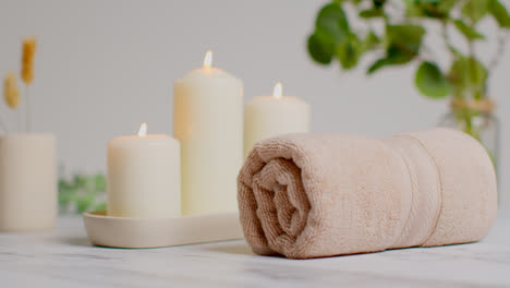 Still-Life-Of-Lit-Candles-With-Dried-Grasses-Green-Plant-And-Soft-Towels-As-Part-Of-Relaxing-Spa-Day-Decor